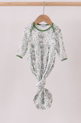 Green and white patterned baby outfit on a hanger against a light background