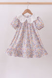 Floral dress with a lace collar on a hanger against a plain background Aaria Tees