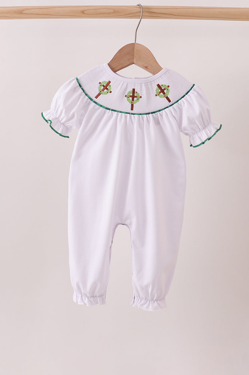 White baby romper with embroidered details on a wooden hanger against a beige background Aaria Tees