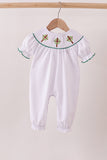 White baby romper with embroidered details on a wooden hanger against a beige background Aaria Tees