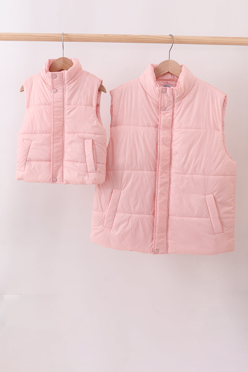 Two pink puffer vests hanging on a rack against a white background Aaria Tees