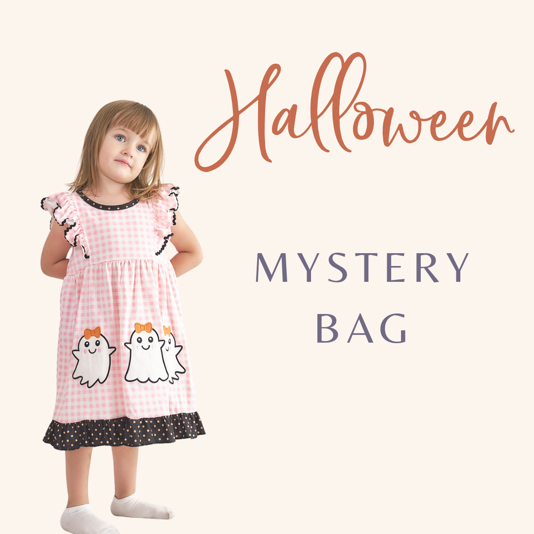 A young child wearing a pink dress with a Halloween theme, including two white ghosts, standing against a white background with the text 'Halloween' and 'MYSTERY BAG' added visually. Aaria Tees