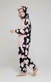 Person wearing a cow-themed onesie with pink hearts on a white background Aaria Tees